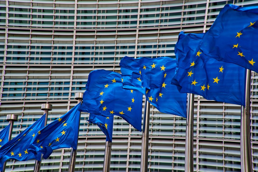 Acht Flaggen der Europäischen Union wehen auf ihrem Fahnenmast vor dem Gebäude der Europäischen Kommission, Nahaufnahme, die Flaggen sind das Zentrum des Bildes