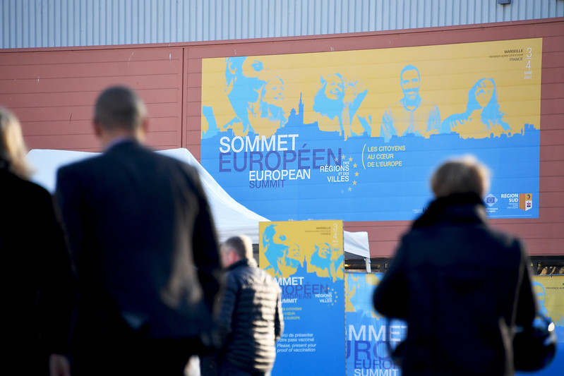 Wand mit der Aufschrift "Sommet Marseille" und Menschen die herumlaufen