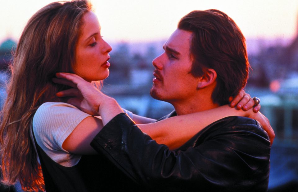 Filmszene: Ein junges Paar schaut sich verliebt in die Augen, umarmt sich vor romantischem Abendlicht.